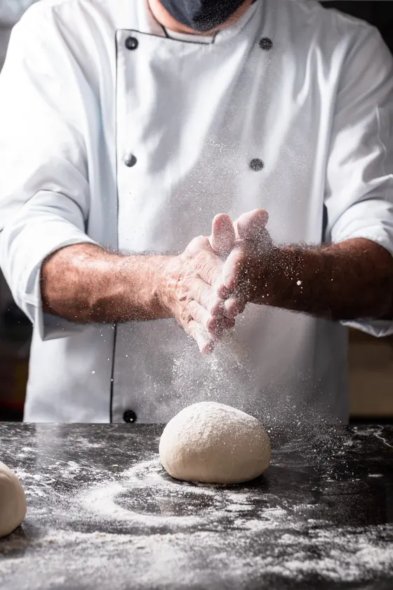 Chef sovando massa de pão registrado em ensaio de fotografia gastronômica de processo artesanal